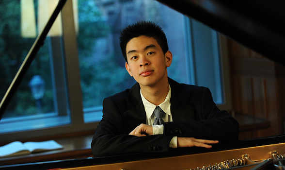 Andrew Hsu leaning on piano
