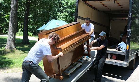 gentleman helping load piano in back of truck