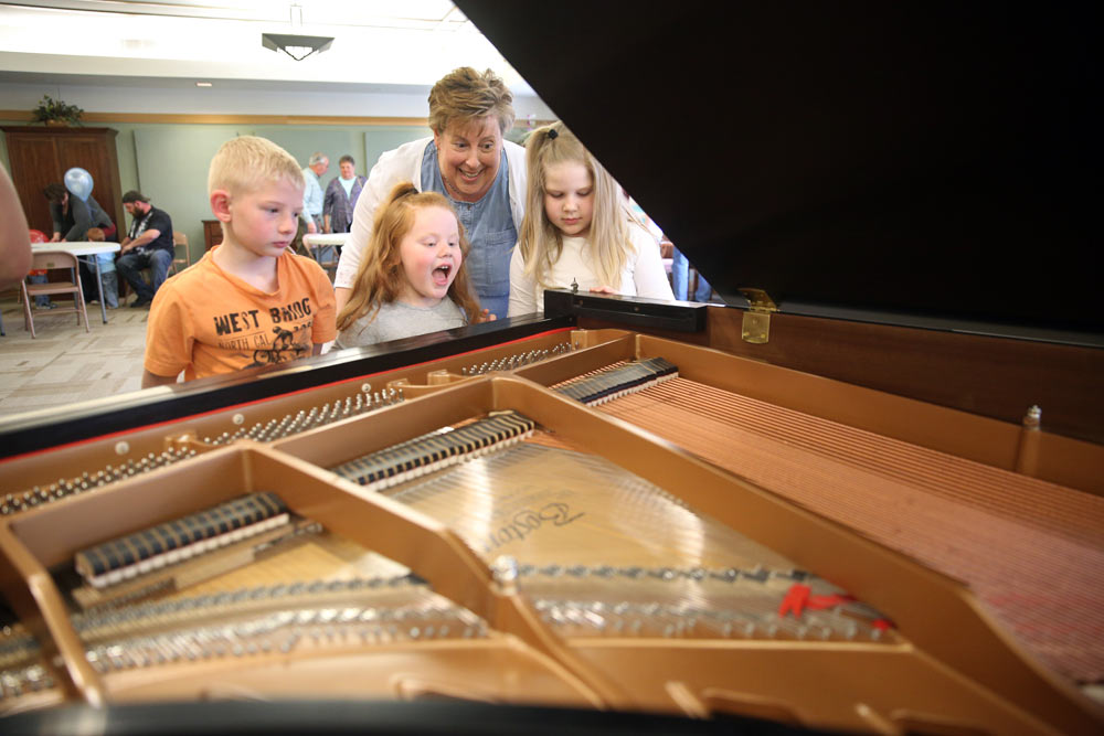 little kids looking inside of a piano