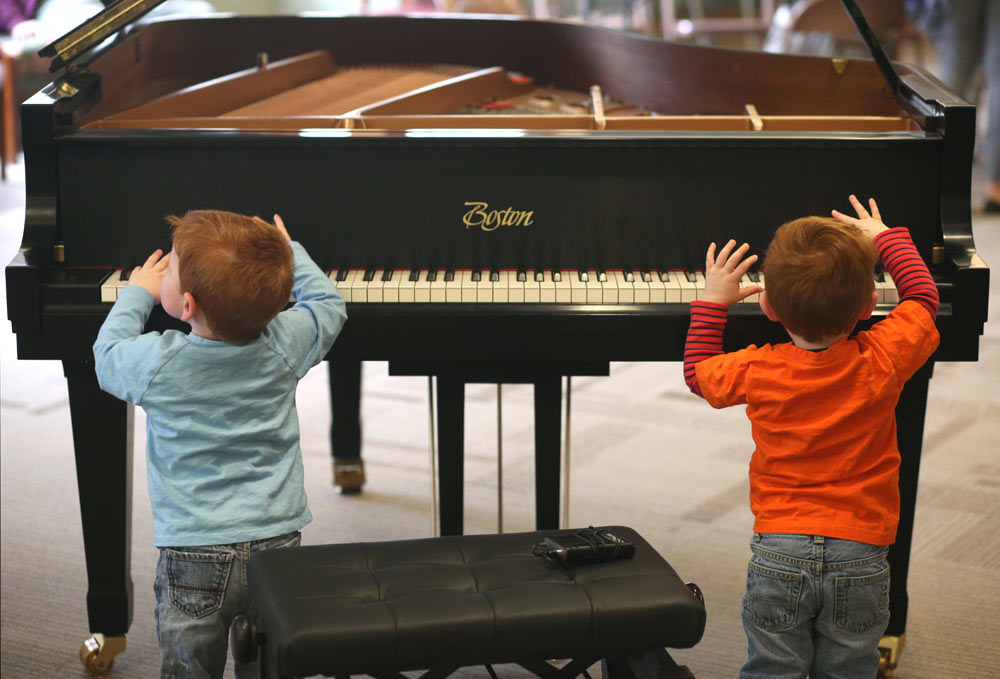 two kids playing with the keyboard on the piano