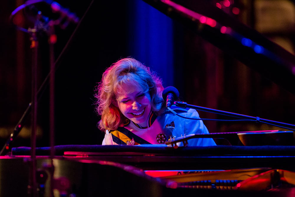 Nellie McKay smiling while playing the piano