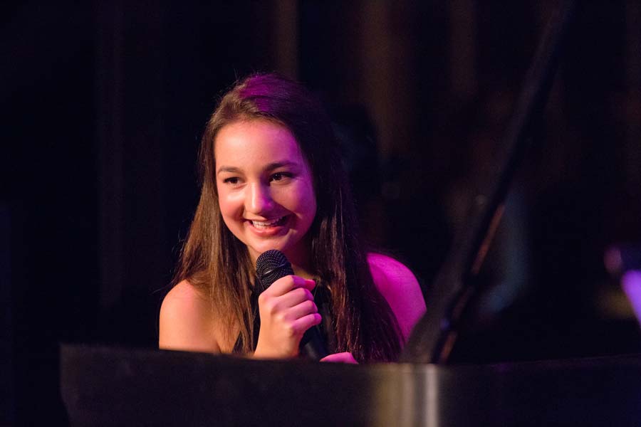 the Emily Bear Trio smiling at the audience while holding a microphone