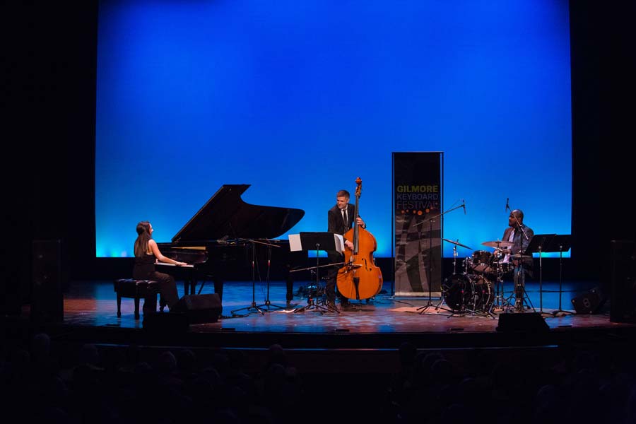 the Emily Bear Trio on stage together with a blue background