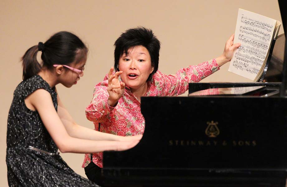 Katherine Chi holding music and instructing student