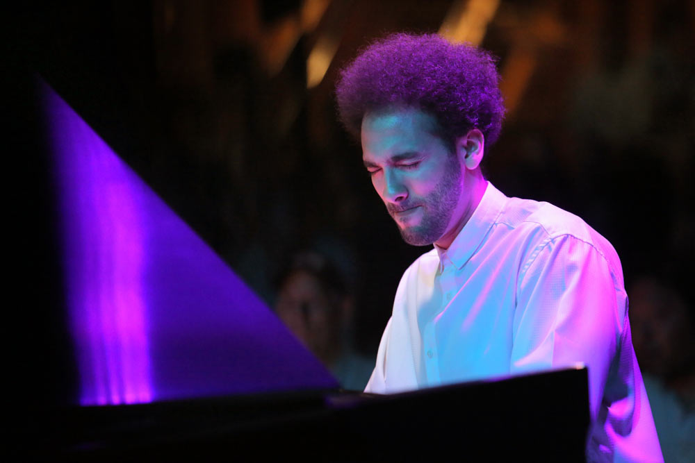 close up of David Virelles playing piano on stage