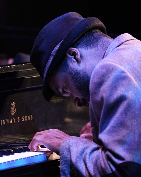 the Sullivan Fortner Trio's pianist leaning over the piano