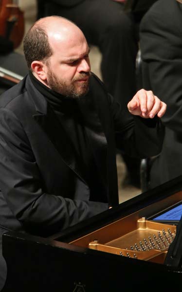 Kirill Gerstein at the piano reading music off a tablet