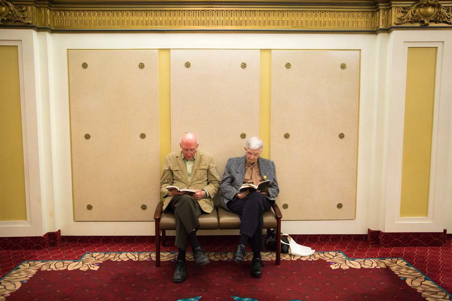 two gentleman sitting down reading a book