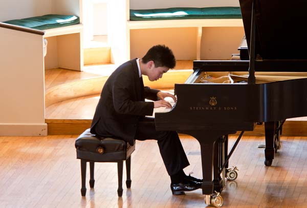 Andrew Hsu performing on black piano
