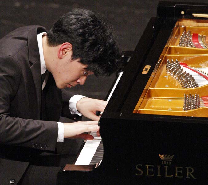 Daniel Hsu leaned over the piano