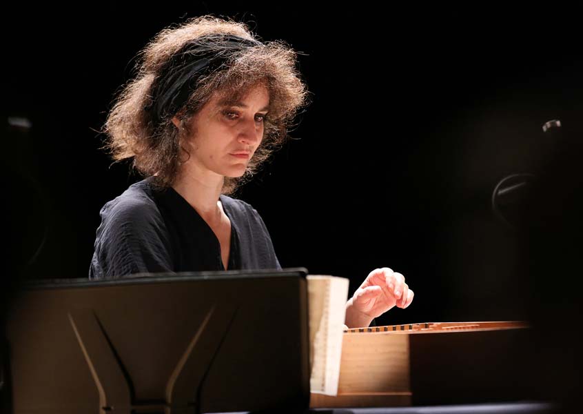 Corina Marti looking down at her wooden piano