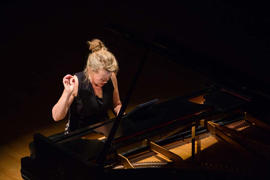Lisa Moore with one hand raised while playing the piano