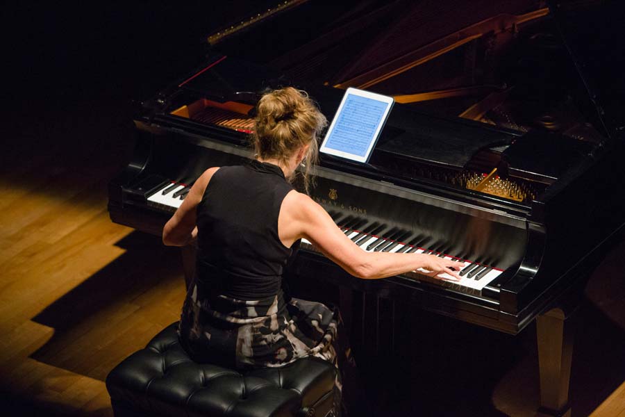 Lisa Moore reading from a tablet while playing the piano