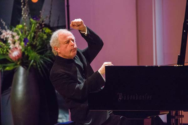 Sir András Schiff playing piano with one hand in the air