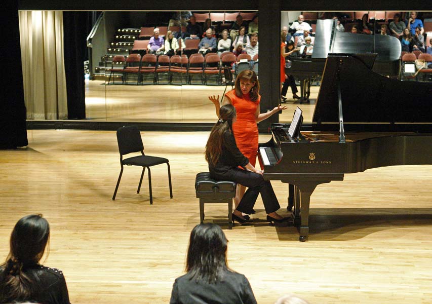 Lori Sims on stage with a student while audience members look on