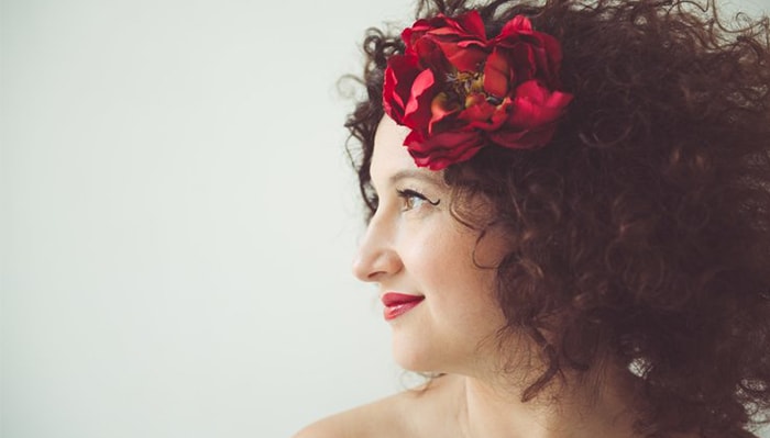 a side portrait of svetlana smiling with a red flower in her hair