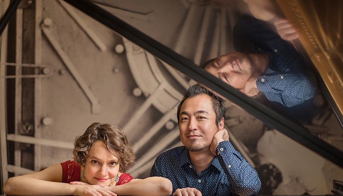 Eva-Maria Zimmerman and Keisuke Nakagoshi pose for a portrait with a piano