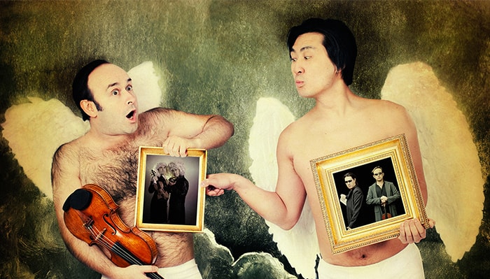 two adult cherubs hold rfames with pictures of igudesman & joo in them