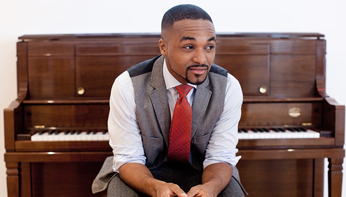 Sullivan Fortner sits in front of a piano