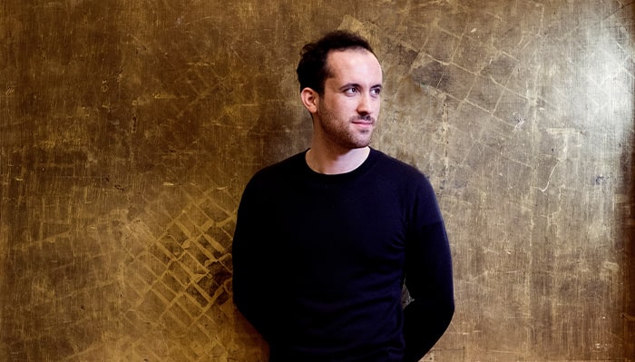 igor levit poses for a portrait in front of a textured wall