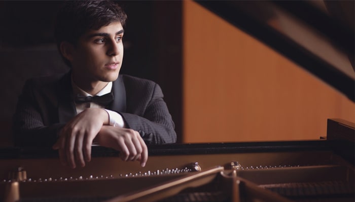 portrait of evren ozel sitting at a piano and looking into the distance