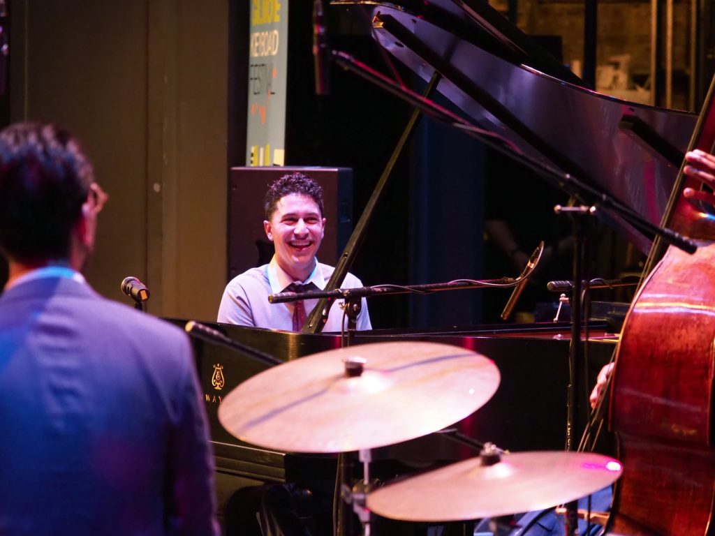 Emmet Cohen Trio pianist laughing on stage