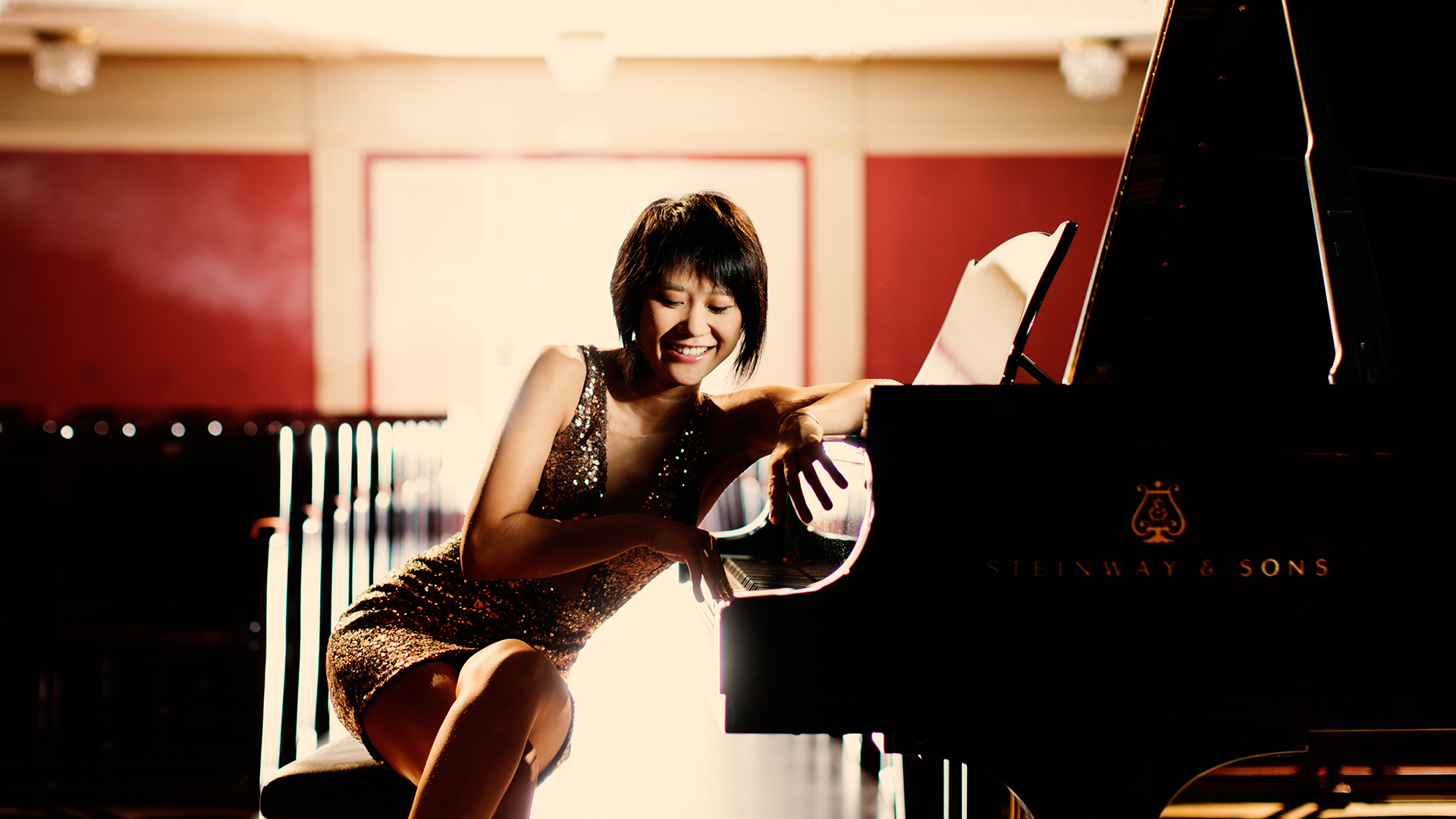 Yuja Wang sitting at a piano dressed elegantly