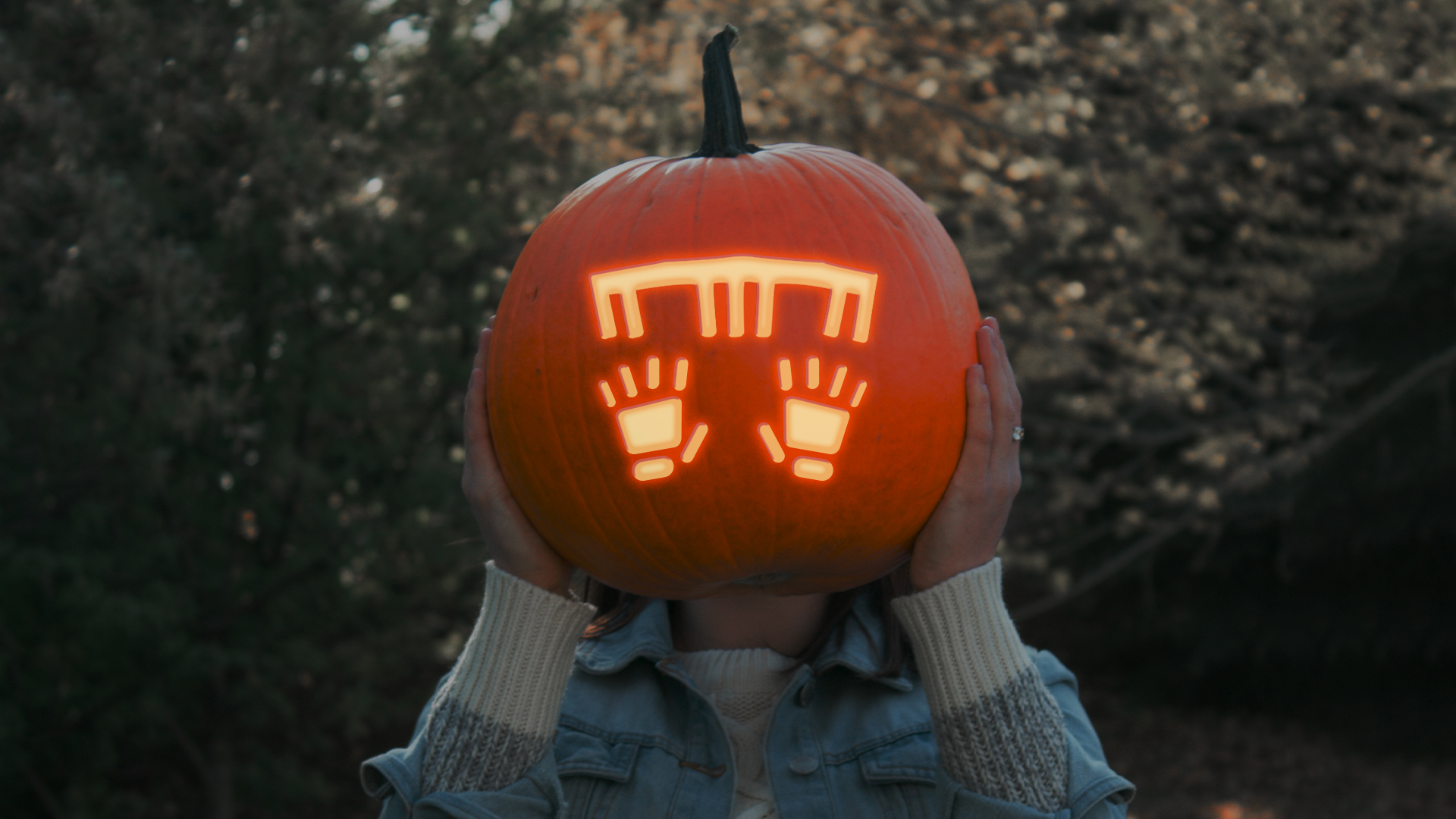 girl holding pumpkin carving of hands and a piano in front of face