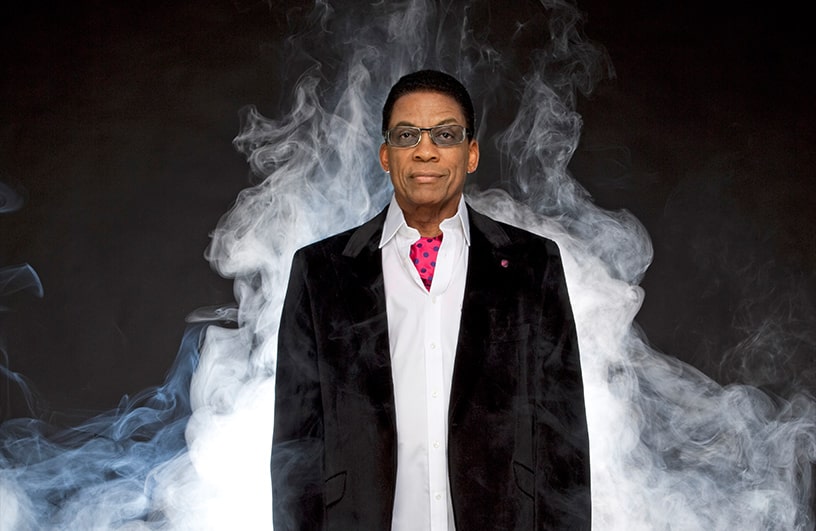 herbie hancock poses in front of a cloud of smoke