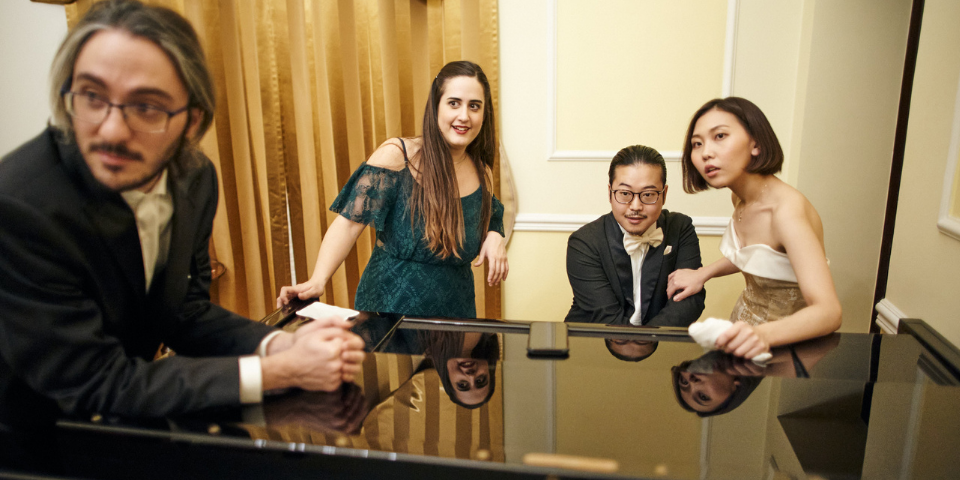 A group of people standing around a piano